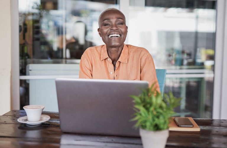 Mulher sentada, feliz, em frente de um notebook