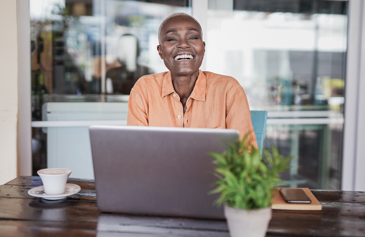 Mulher sentada, feliz, em frente de um notebook
