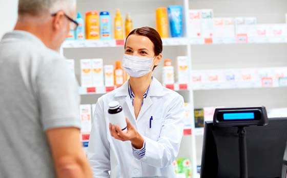 Mulher farmacêutica, em farmácia, entregando medicamento a um homem