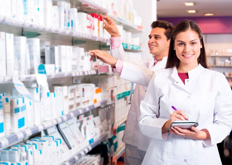 Dois farmacêuticos em uma farmácia, perto de prateleira com muitos medicamentos