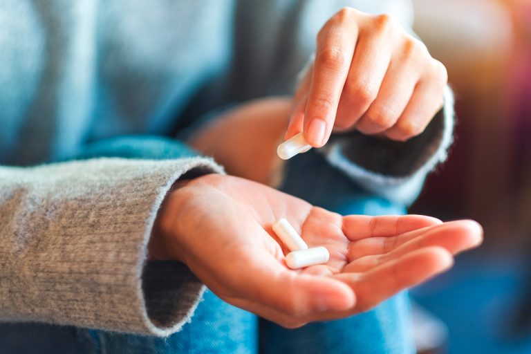 Grupo EP epharma Mulher com 3 comprimidos de medicamento em suas mãos